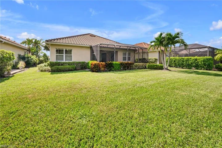 Rear view of house featuring a lawn and a lanai