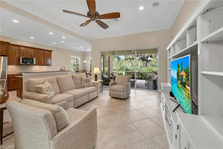 Living room with ceiling fan, light tile patterned flooring, a healthy amount of sunlight, and crown molding