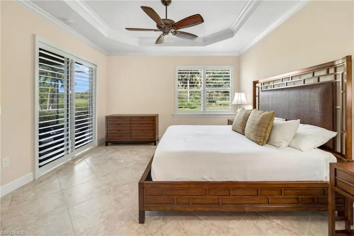 Bedroom with ornamental molding, ceiling fan, and a raised ceiling