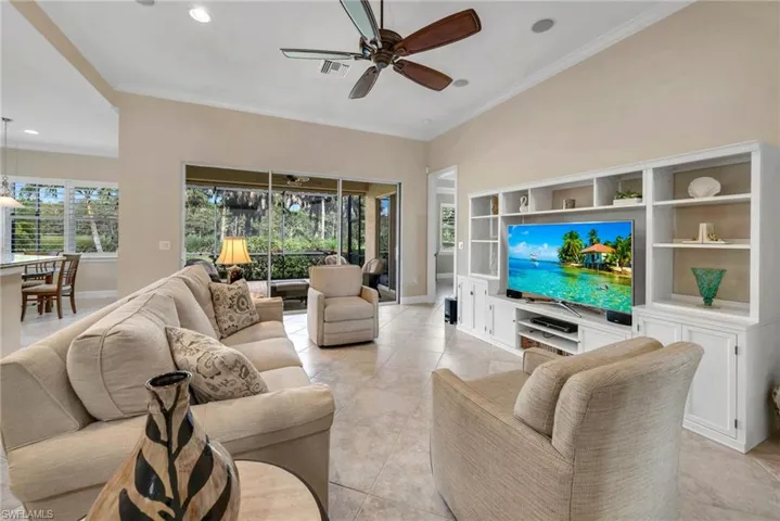Tiled living room with ornamental molding and ceiling fan