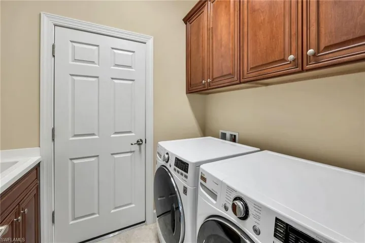 Laundry room with cabinets, light tile patterned flooring, and washer and dryer