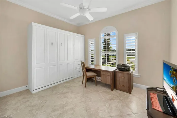 Office space featuring crown molding, light tile patterned flooring, and ceiling fan
