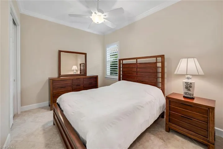 Tiled bedroom with ceiling fan, a closet, and ornamental molding
