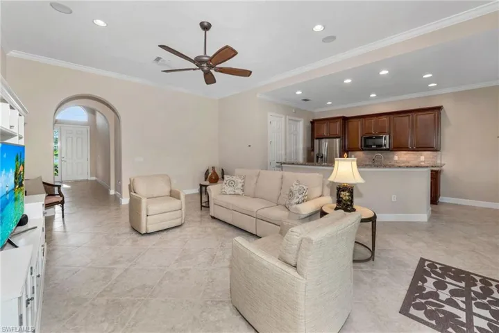 Tiled living room with crown molding, sink, and ceiling fan