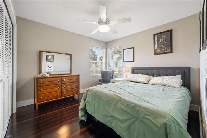 Bedroom with dark wood-type flooring, ceiling fan, and a closet