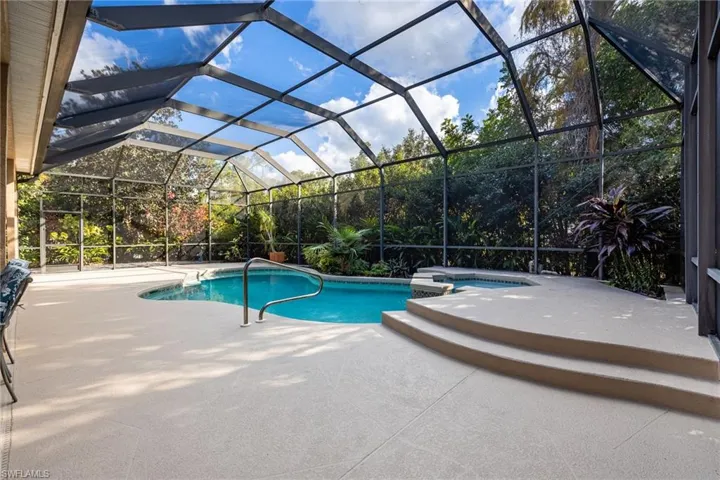 View of swimming pool featuring a sunroom, glass enclosure, a patio, and a pool with connected hot tub
