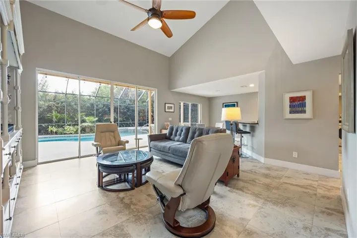 Living room with high vaulted ceiling, ceiling fan, and a sunroom