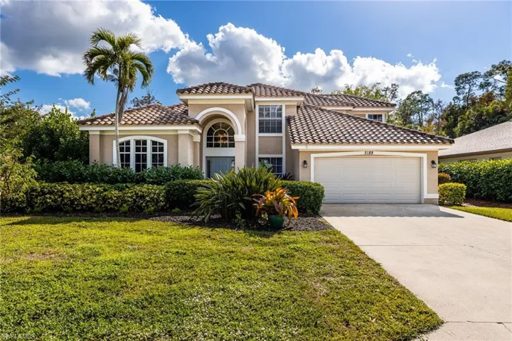 Mediterranean / spanish house with stucco siding, concrete driveway, a front yard, a tile roof, and an attached garage