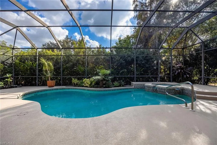 View of swimming pool with a lanai, a sunroom, a pool with connected hot tub, and a patio