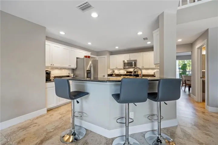 Kitchen featuring a breakfast bar area, white cabinetry, a peninsula, appliances with stainless steel finishes, and tasteful backsplash