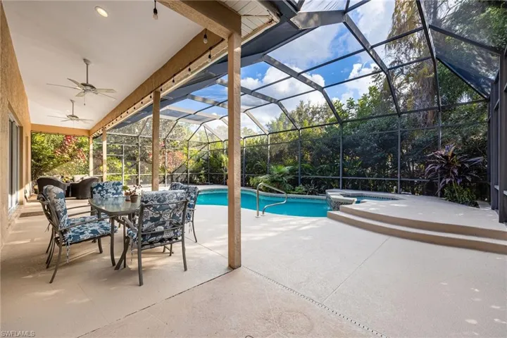 View of pool with a patio area, a sunroom, a pool with connected hot tub, and glass enclosure