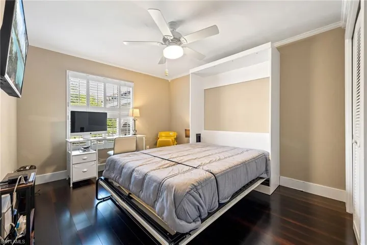 Bedroom featuring ornamental molding, dark wood-style floors, and a ceiling fan