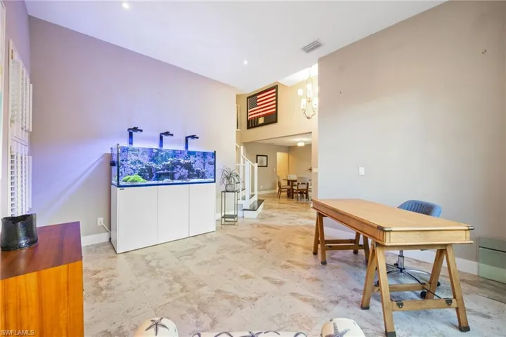 Office space featuring a towering ceiling, a chandelier, and light flooring