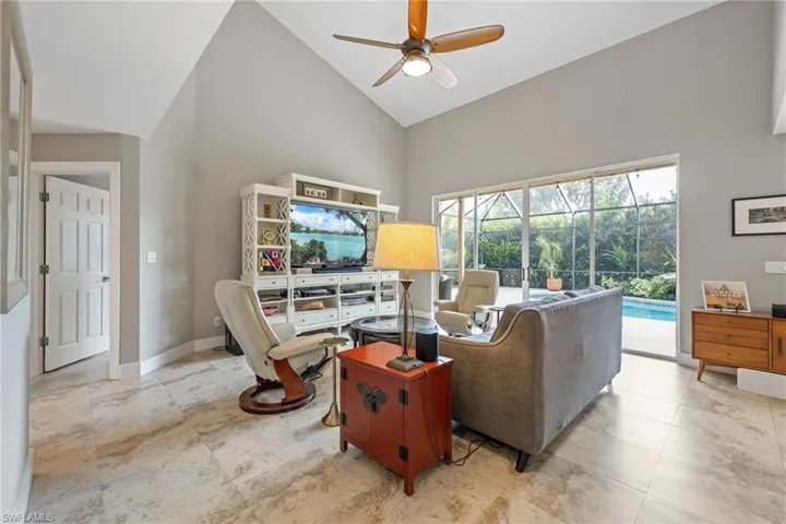 Living room featuring high vaulted ceiling, ceiling fan, and a sunroom