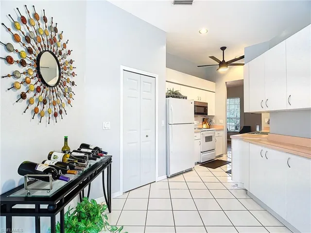 Kitchen featuring white cabinets, ceiling fan, white appliances, and light tile flooring