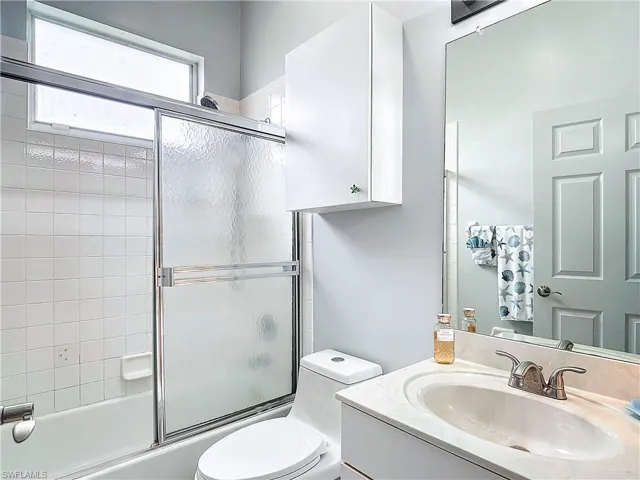 Full Guest Bathroom featuring combined bath / shower with glass door, vanity, and toilet