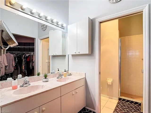 Bathroom with walk in shower, dual bowl vanity, and spacious walk-in closet
