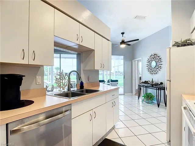 Kitchen with ceiling fan, white cabinetry, stainless steel dishwasher, sink, and light tile floors
