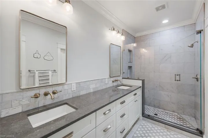Gorgeous updated master bath with dual vanity with integrated sinks, quartz counters, and wall-mounted faucets