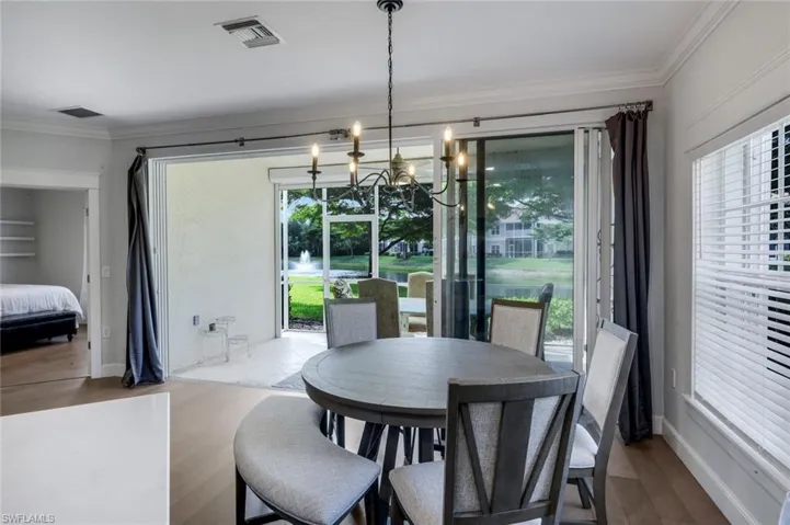 Dining area featuring a contemporary chandelier, LVP flooring, and crown molding