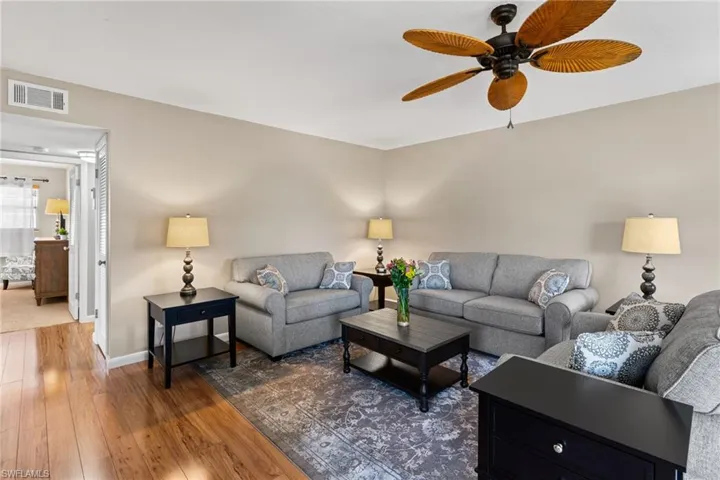 Living room with dark wood-style floors and a ceiling fan