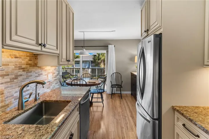 Kitchen with stainless steel appliances, light stone countertops, backsplash, and cream cabinetry