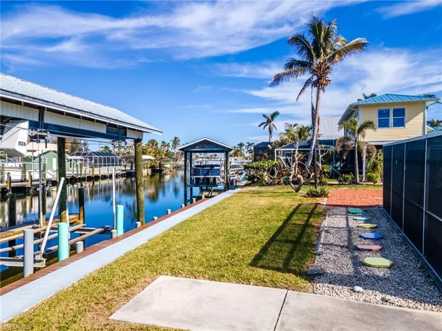 Dock area with a yard, a water view, and glass enclosure