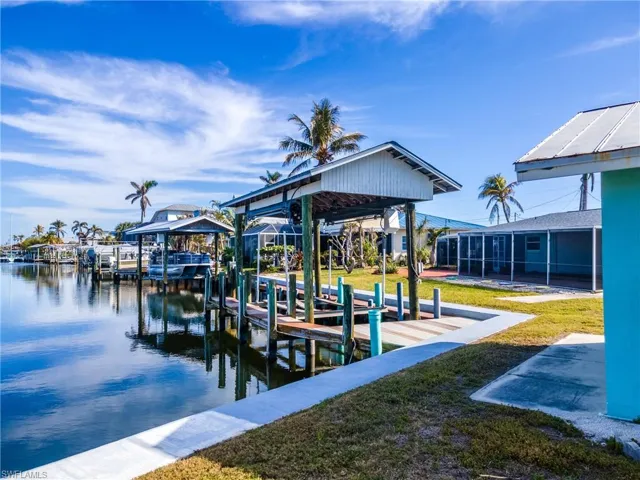View of dock with a water view and a lawn