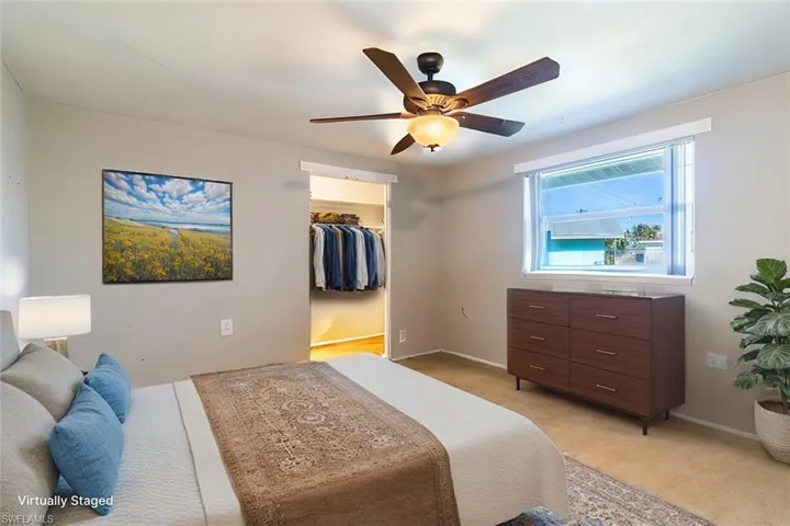 Carpeted bedroom featuring ceiling fan, a spacious closet, and a closet (virtually staged)