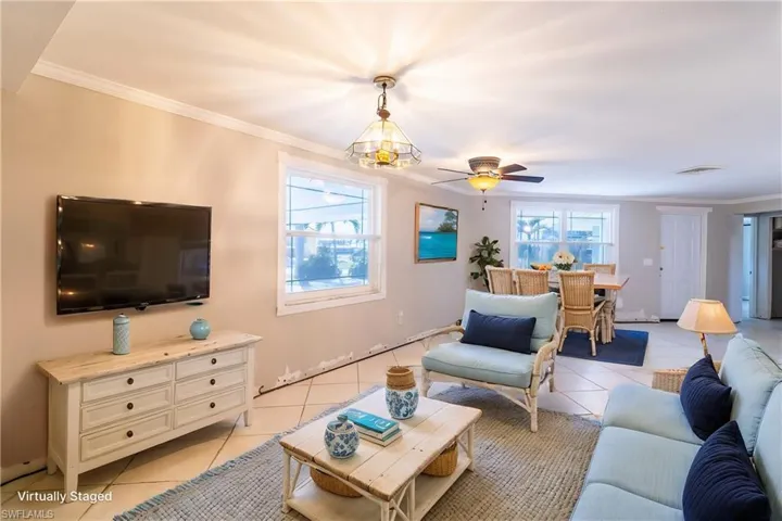 Tiled living room featuring ornamental molding and ceiling fan  (virtually staged)