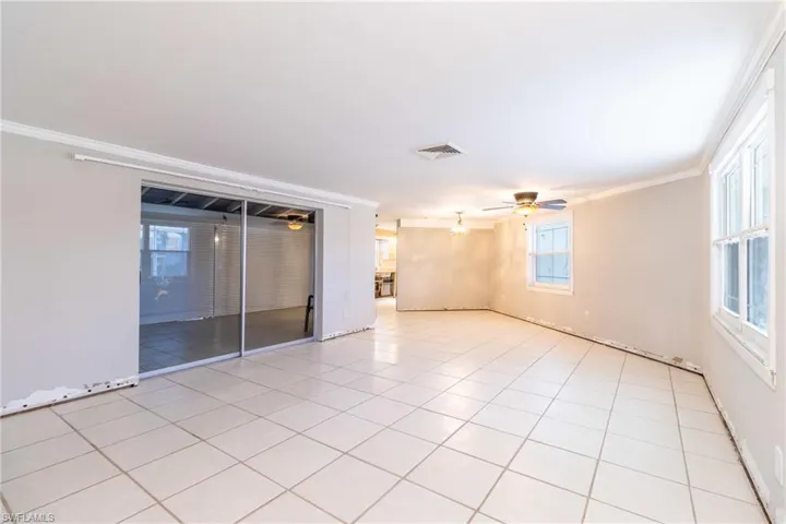 Spare room featuring light tile patterned flooring, ceiling fan, and ornamental molding