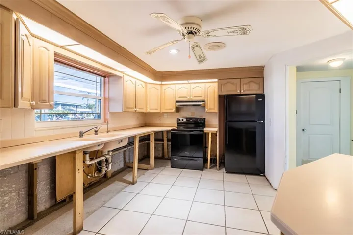 Kitchen featuring tasteful backsplash, light tile patterned floors, black appliances, and light brown cabinets