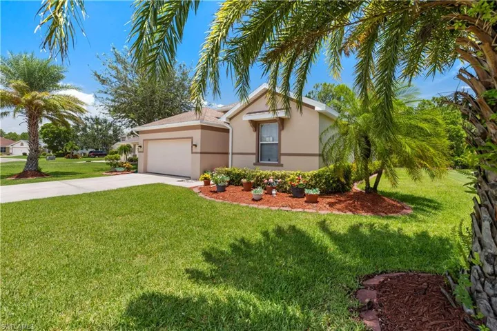 View of front of property featuring concrete driveway, stucco siding, a front yard, and a garage