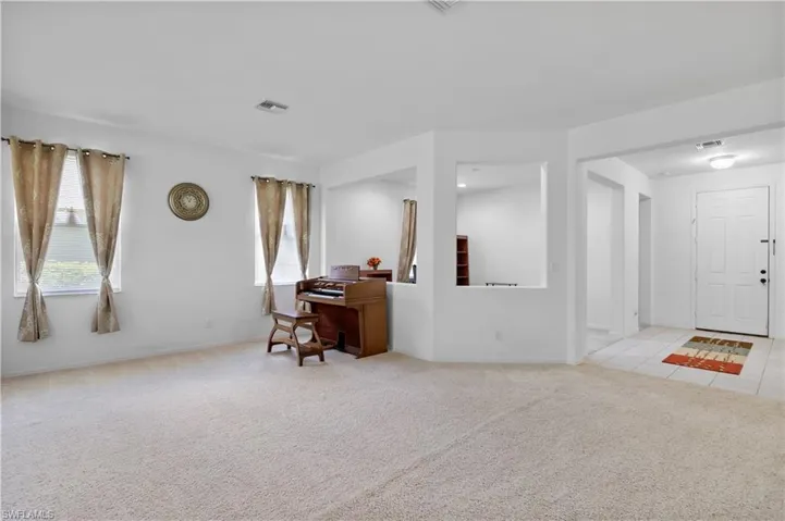 Empty room featuring light colored carpet and a desk