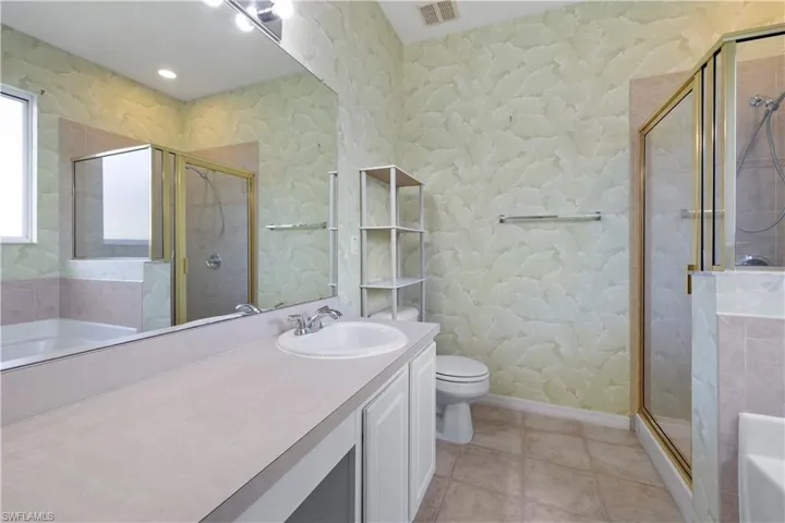 Bathroom with a bath, a shower stall, vanity, light tile patterned floors, and recessed lighting