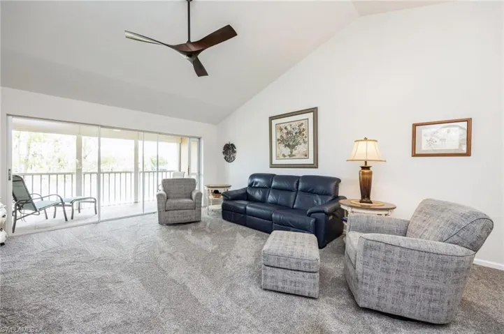 Carpeted living room with high vaulted ceiling, ceiling fan, and a wealth of natural light