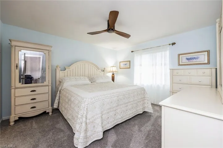 Bedroom with ceiling fan and dark colored carpet