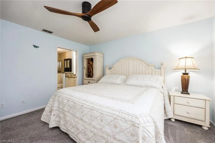 Carpeted bedroom with ceiling fan and ensuite bathroom