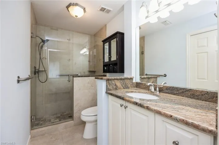 Bathroom with a shower with shower door, vanity, toilet, and tile floors