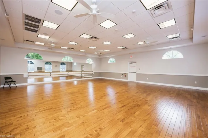 Spare room featuring a tray ceiling, ceiling fan, light hardwood / wood-style flooring, and a drop ceiling