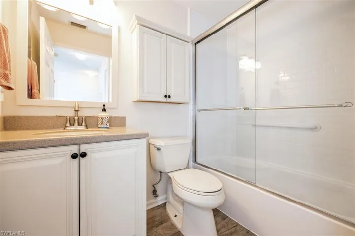 Full bathroom featuring combined bath / shower with glass door, toilet, hardwood / wood-style flooring, and vanity