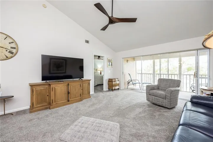 Carpeted living room featuring high vaulted ceiling and ceiling fan