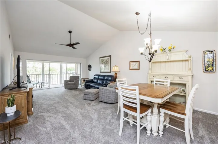 Dining area featuring lofted ceiling, carpet, and ceiling fan with notable chandelier