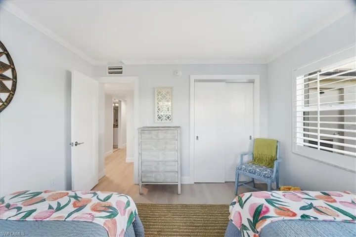 Bedroom featuring crown molding, light wood-type flooring, and a closet