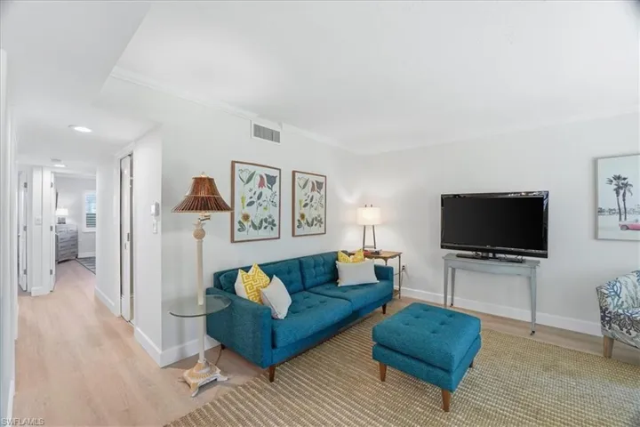 Living area with wood finished floors, ornamental molding, and recessed lighting