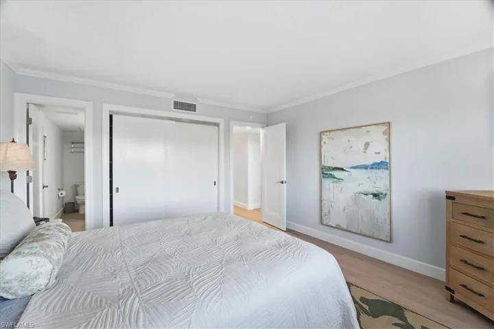 Bedroom with crown molding, a closet, and light wood-style flooring