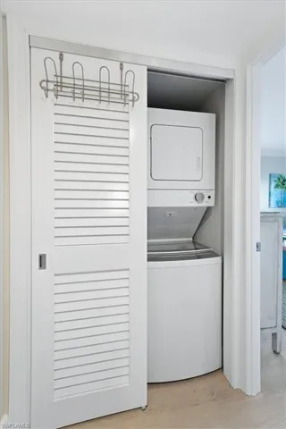 Laundry room featuring stacked washer / drying machine and light wood-style flooring