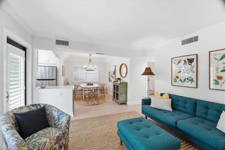 Living area featuring light wood-style flooring, a chandelier, and ornamental molding