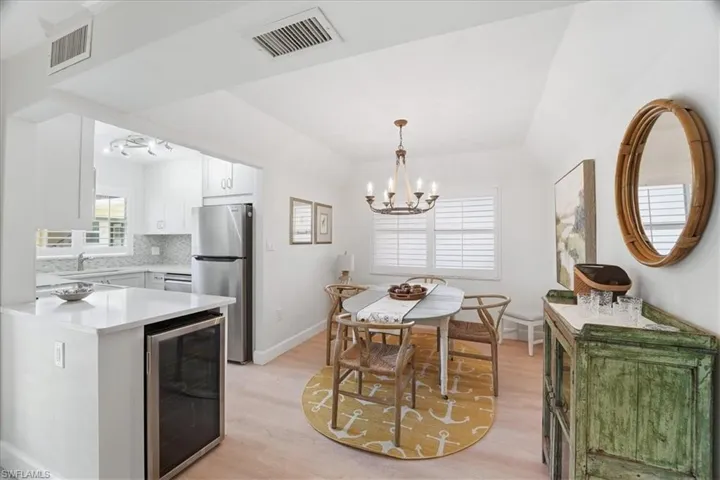 Kitchen featuring wine cooler, freestanding refrigerator, white cabinets, pendant lighting, and a chandelier