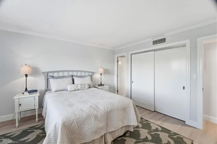 Bedroom with light wood-style floors, a closet, and crown molding